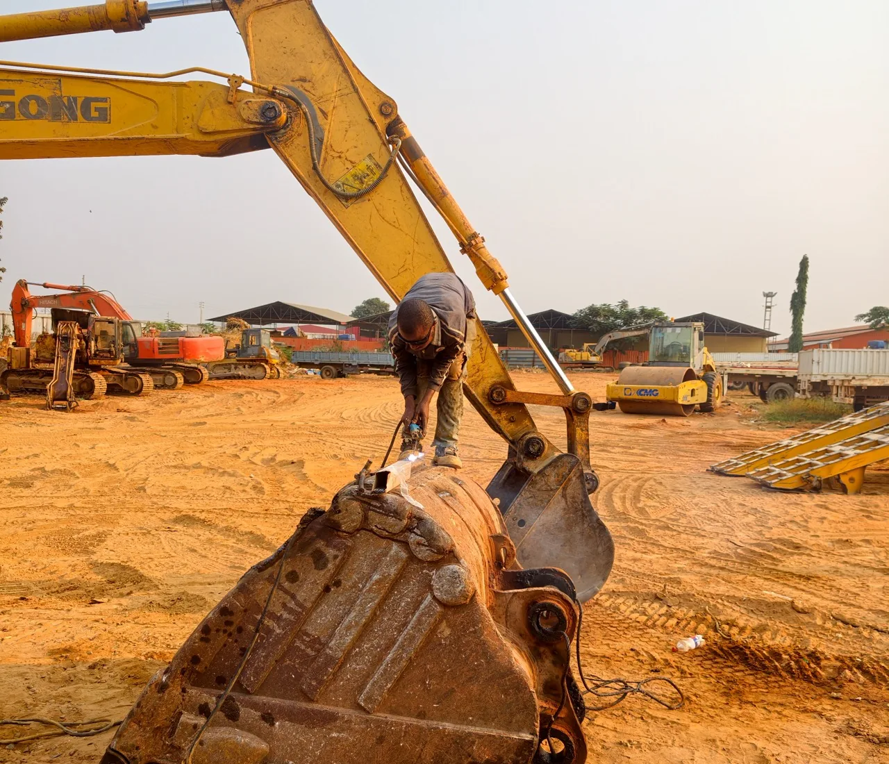 Técnico a realizar uma intervenção mecânica no balde de uma escavadora em Angola